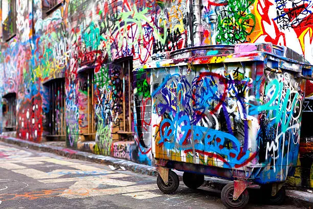 Photo of Dumpster and wall covered with colorful graffiti