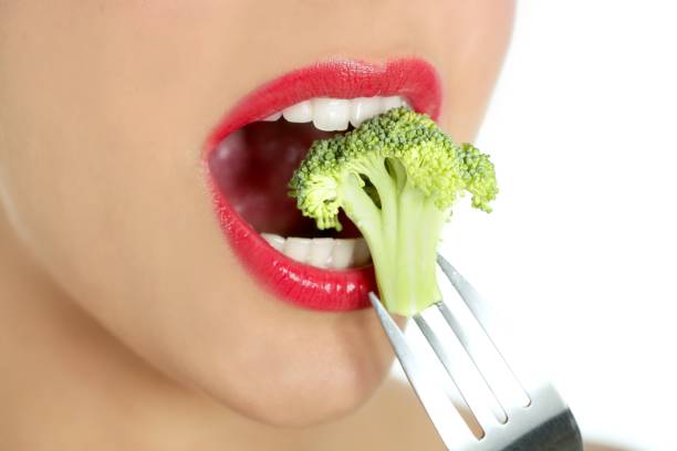 istock Broccoli on steel fork in woman mouth 1350848443
