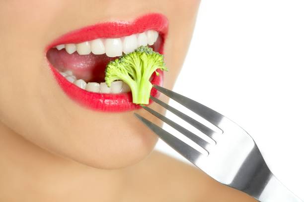 istock Broccoli on steel fork in woman mouth 1350848468