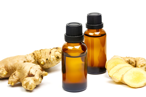 Ginger essential oil in bottle and fresh ginger with sliced isolated on white background. The scientific name is zingiber officinale. Herbs for health care concept.