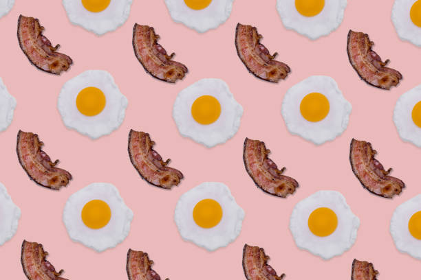 istock Pattern made with fried eggs and slices of crispy bacon on bright pink background. 1350851605