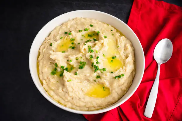 A large bowl of whipped potatoes topped with chives and melted butter