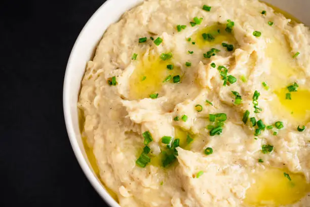 A large bowl of whipped potatoes topped with chives and melted butter