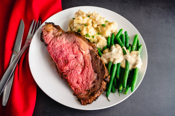 Prime Rib Served with Garlic Mashed Potatoes and Green Beans Medium-rare prime rib dinner served with side dishes on a white plate green bean vegetable bean green stock pictures, royalty-free photos & images