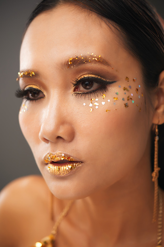 Face of attractive young Asian woman with beautiful eye make-up and glitter on face