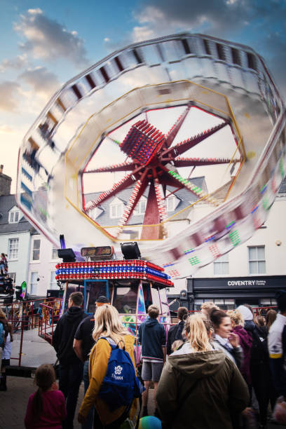 menschenmassen, die den nervenkitzel und die verschüttungen der jährlichen mop fair in cotswold, stadt cirencester, gloucestershire, genießen, die am 1. montag im oktober stattfindet - the thrills stock-fotos und bilder