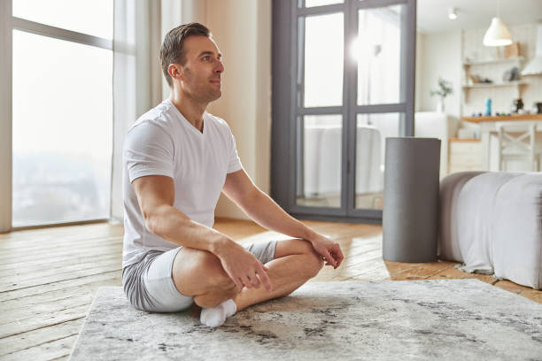 istock Calm male practicing meditation alone at home 1350853381