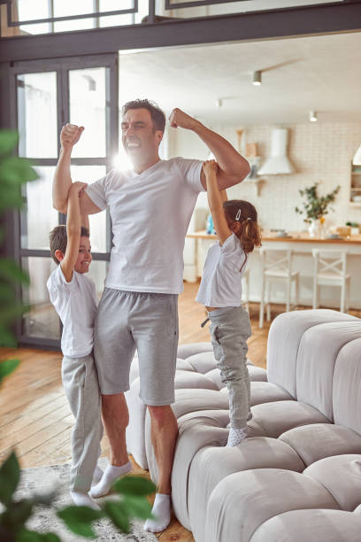 istock Strong dad showing muscles to kids at home 1350853384