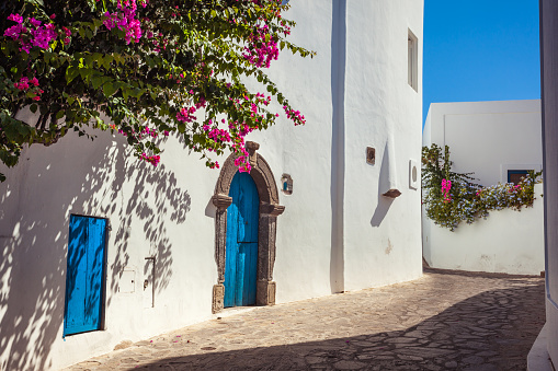 Panarea, Italy - Aug 4, 2010: Street on Panarea island with typical white walls and blue doors and bougainvillea flowers