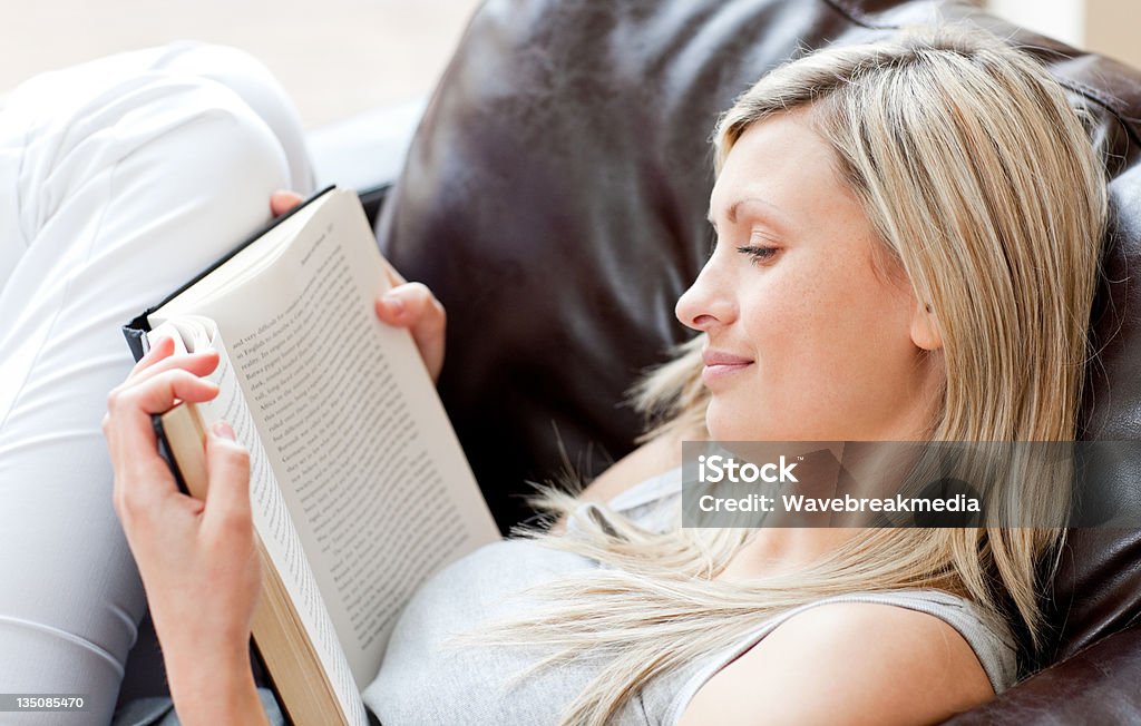 Charmante femme lisant un livre assis sur le canapé-lit - Photo de Adulte libre de droits