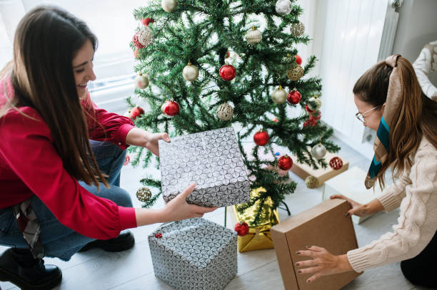 istock Two women placing presents under a Christmas tree 1350854913