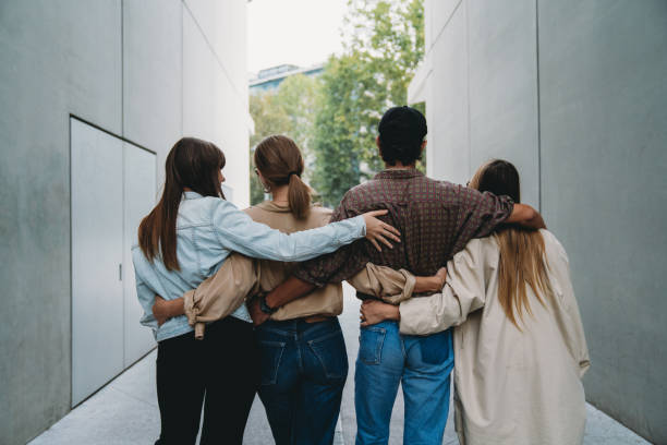 istock Rear view of four friends embracing together 1350856549