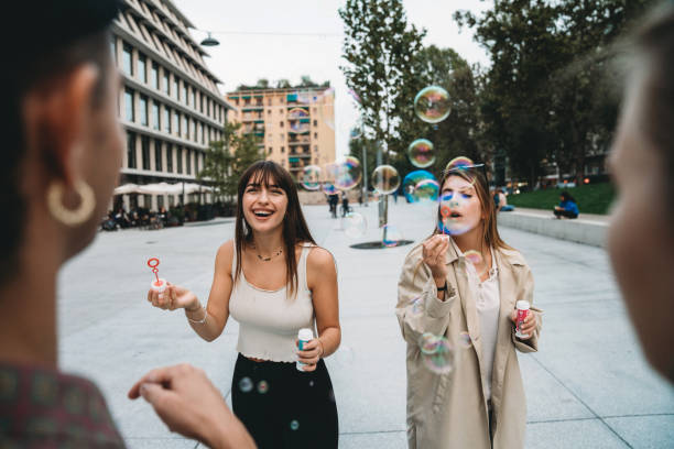 istock Friends playing with soap bubbles together in the city 1350856562