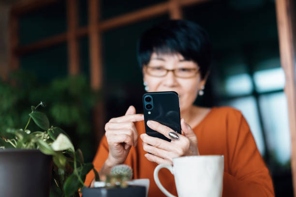 istock Senior Asian woman using smartphone while relaxing at home. Elderly and technology 1350856661
