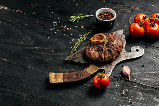 grilled veal Osso Buco steak on metal meat cleaver on black background. Top view grilled veal Osso Buco steak on metal meat cleaver on black background. Top view. ossobuco stock pictures, royalty-free photos & images