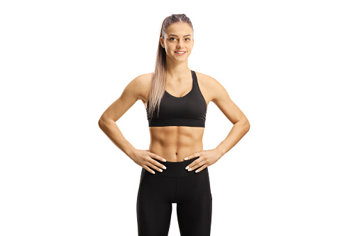 YÐ¾ung female in crop top and leggings smiling isolated on white background