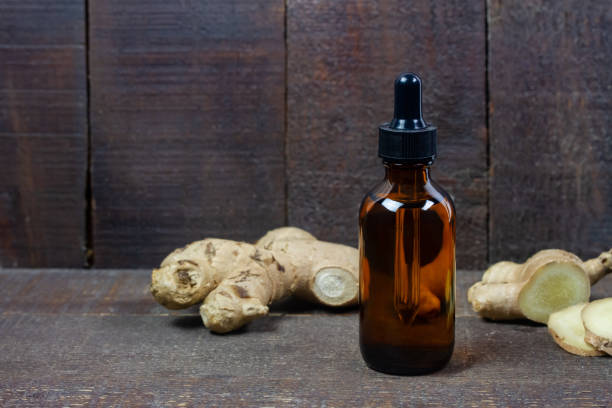 istock Ginger essential oil in bottle and fresh ginger with sliced on rustic wooden background. 1350864352