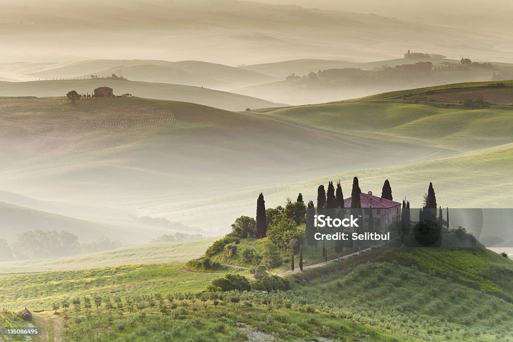Farmhouse in Tuscany Picturesque and idyllic view on farmhouse at sunrise near Pienza and San Quirico d´Orcia in Tuscany, Italy. Morning fog and haze between hills are very common in spring.  Tuscany Stock Photo