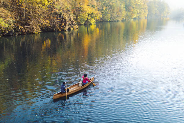 Couple enjoying canoeing on river with beautiful weather and amazing autumn colors
