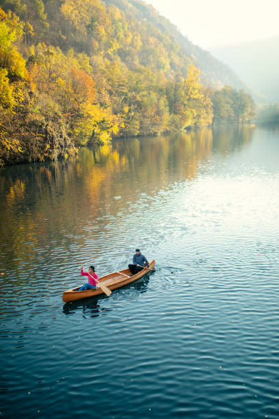 Couple enjoying canoeing on river with beautiful weather and amazing autumn colors