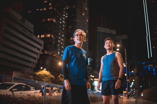 Portrait Asian Chinese active senior man and his son with sport clothing looking away in the city at night confidence