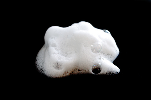 Jabón de burbujas de espuma blanca, limpiador o champú aislado sobre fondo negro photo
