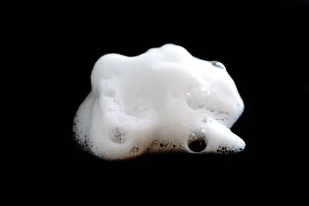 Photo of White foam bubble soap, cleanser or shampoo isolated on black background