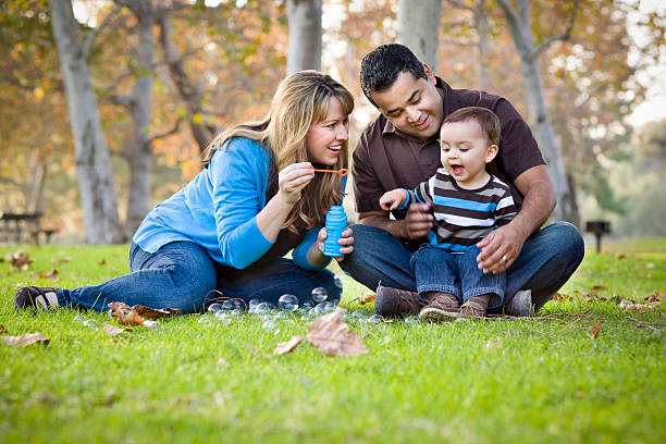 счастливый смешанной расы этнические семья играет с шампанским в парке - family with two children family park child стоковые фото и изображения