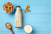 Vegan peanut milk in glass bottle with peanuts on wooden board