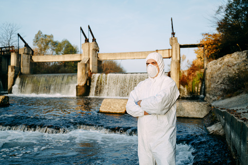Portrait of ecologist with protective suit preparing to examine the pollution of river