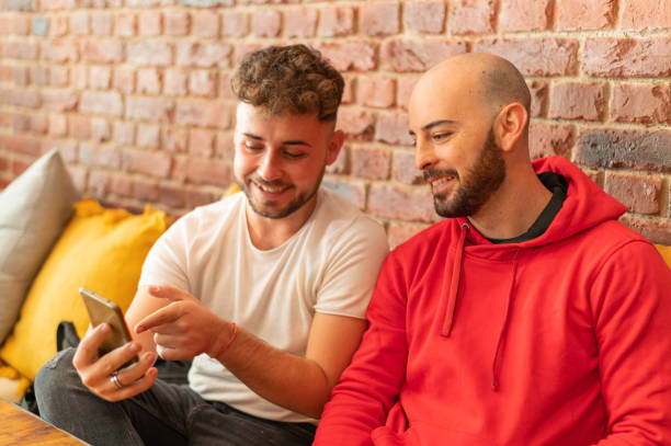 istock Two young bearded men sitting in a cafe enjoying talking while looking at mobile phone. 1350875455