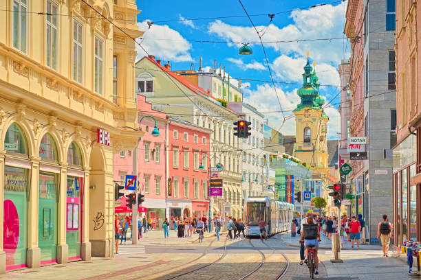 View through the main street of the city with walking people, shops, tram lines, and a tram Linz - June 2020, Austria: View through the main street of the city with walking people, shops, tram lines, and a tram linz austria stock pictures, royalty-free photos & images