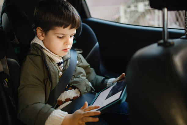 istock Little boy watching cartoon on digital tablet while driving in car with his dad 1350877678