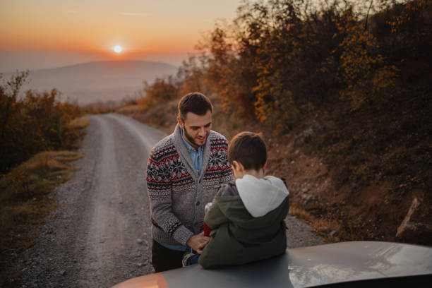 istock Father and son spending time together on a road trip, drinking hot tea from thermos 1350877724