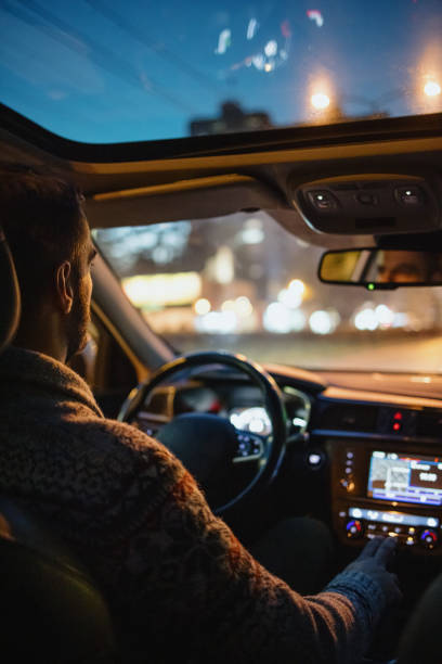 hombre conduciendo coche en las calles de la ciudad por la noche - car driving dashboard night fotografías e imágenes de stock