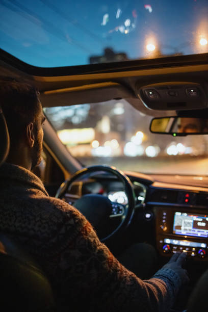 man driving car in the city streets at night - car dashboard night driving imagens e fotografias de stock