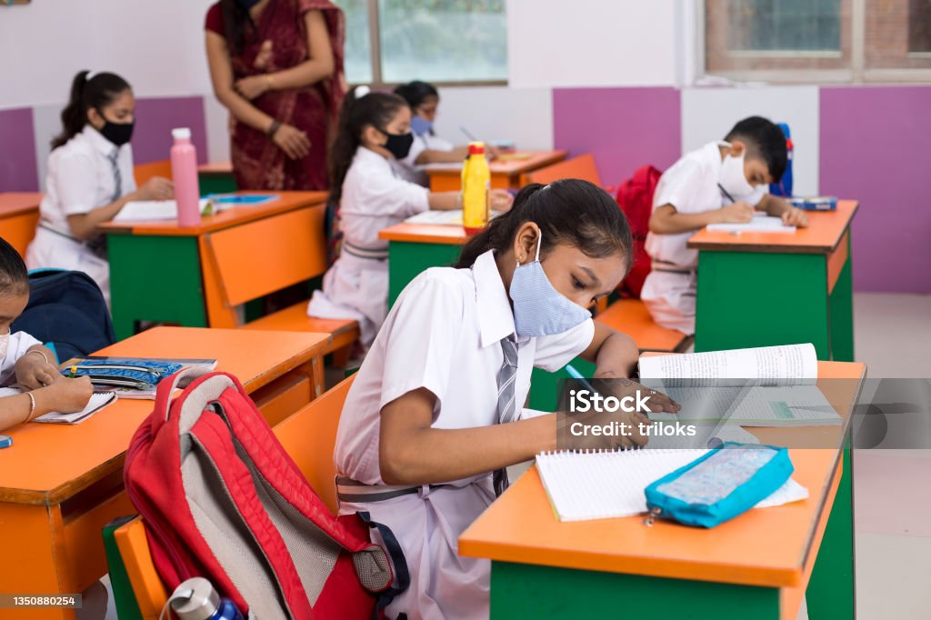 Students in classroom wearing protective face mask after school reopening India Stock Photo