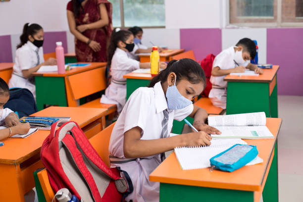 Students in classroom wearing protective face mask after school reopening stock photo