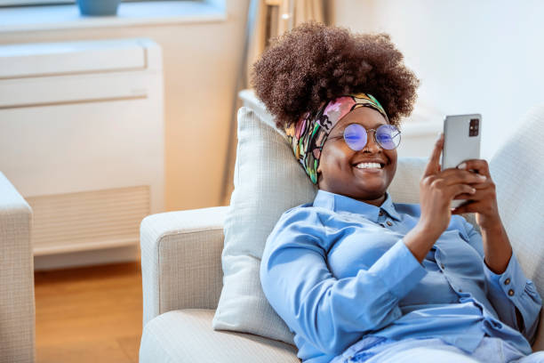 istock Happy woman using smart phone on sofa at home 1350880808