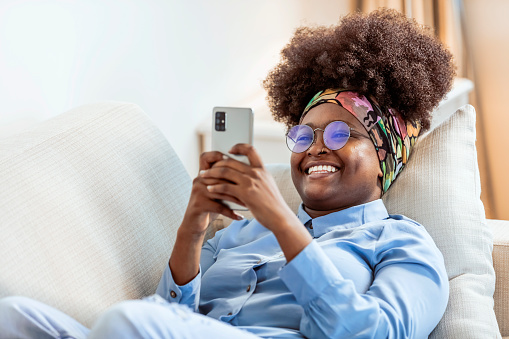 Shot of a relaxed young woman using her phone on the sofa at home