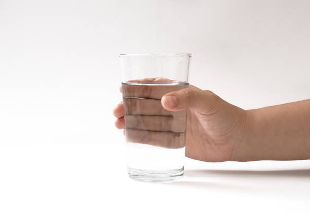 istock hand holding a glass cup on a white background 1350884037