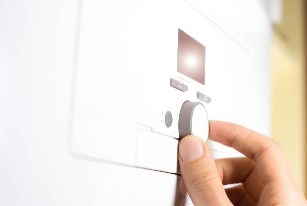 istock Fingers adjust Gas boiler control panel for hot water and heating. Buttons and a digital display. oncept of home heating and heat conservation. 1350884061