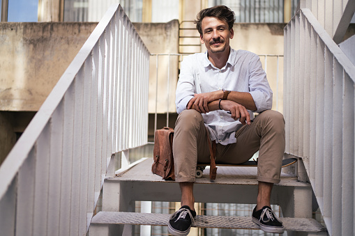 Portrait of an urban and confident young Caucasian entrepreneur, sitting on the stairs