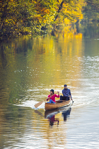 Couple enjoying canoeing on river with beautiful weather and amazing autumn colors