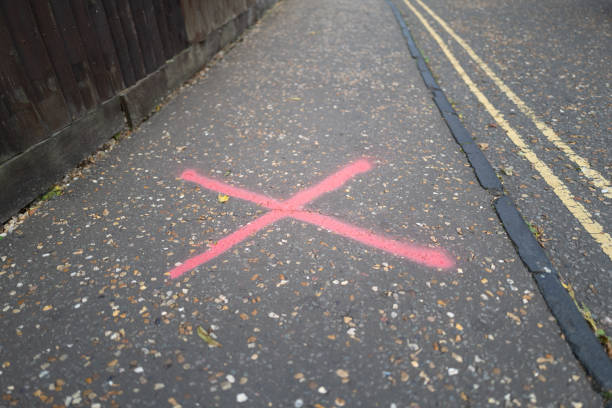 Sprayed cross marker seen on an empty pavement. The marker shows an area of cracking that needs to be repaired. pavement ends sign stock pictures, royalty-free photos & images