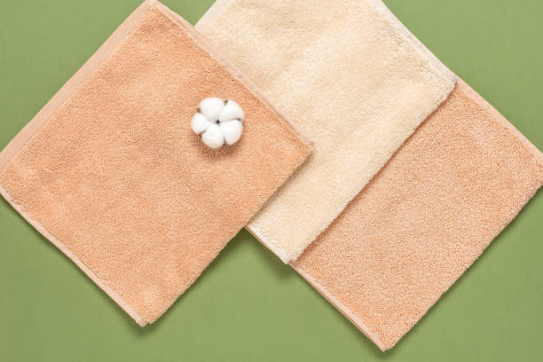 Beige terry towels and cotton flowers on a green paper background. Natural fabrics concept. Top view, flat lay. Beige terry towels and cotton flowers on a green paper background. Natural fabrics concept. Top view, flat lay terry towel stock pictures, royalty-free photos & images