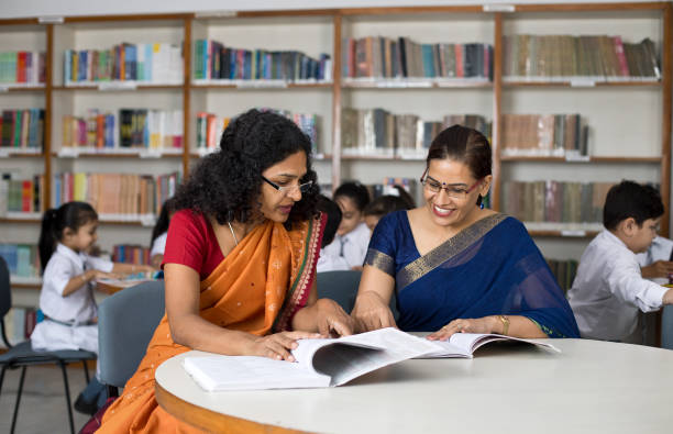 Two teachers discussing over books in library