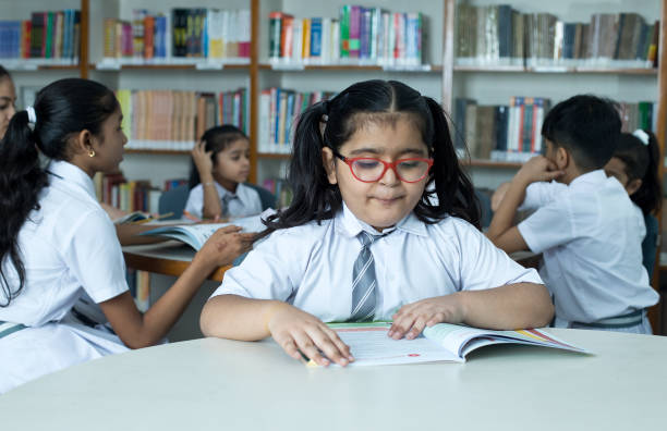istock School children studying book at library 1350887187