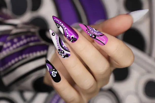 Manicure on long nails with dots and lines.