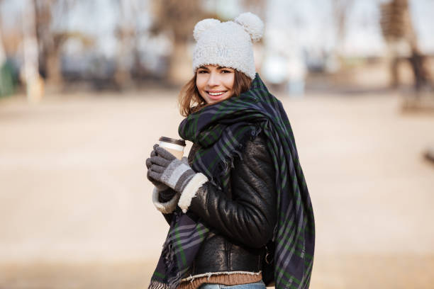istock Smiling woman drinking coffee and walking outdoors in autumn 1350887355
